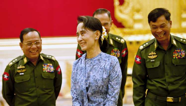 Myanmar's NLD party leader Aung San Suu Kyi smiles with army members during the handover ceremony of outgoing President Thein Sein and new President Htin Kyaw at the presidential palace in Naypyitaw March 30, 2016.