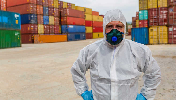 Picture of worker in protective suits in front of container cargo ships