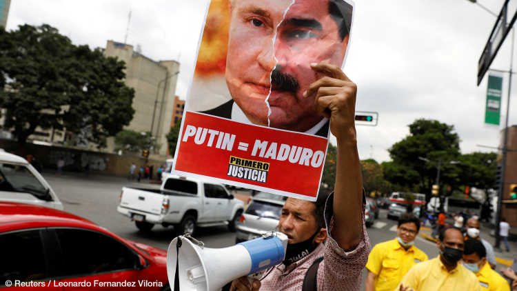 Demonstrator holds a collage of pictures of Russia's President Putin and his Venezuelan counterpart Maduro during an anti-war protest following Russia's invasion, in Caracas, March 4, 2022. The writing on the collage reads "Putin = Maduro, Justice first."